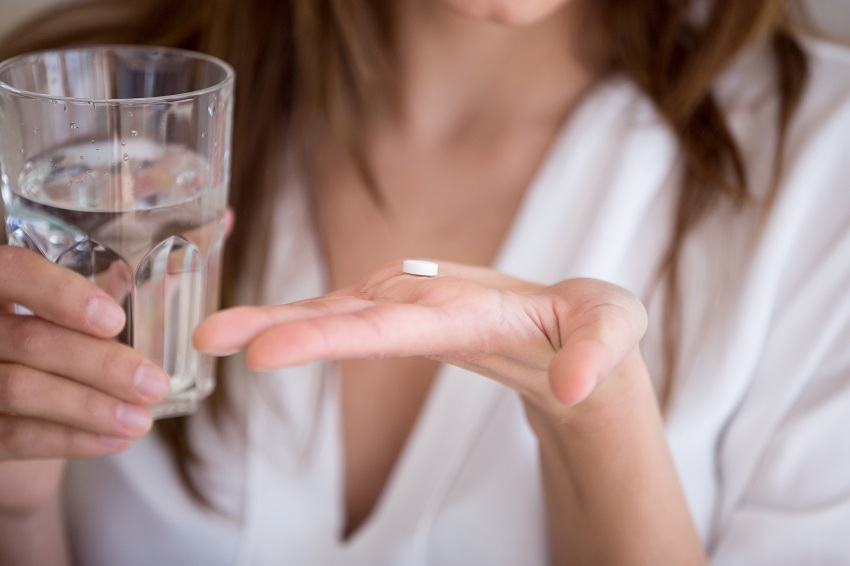 Woman taking antibiotics with water which may influence her gut microbiome